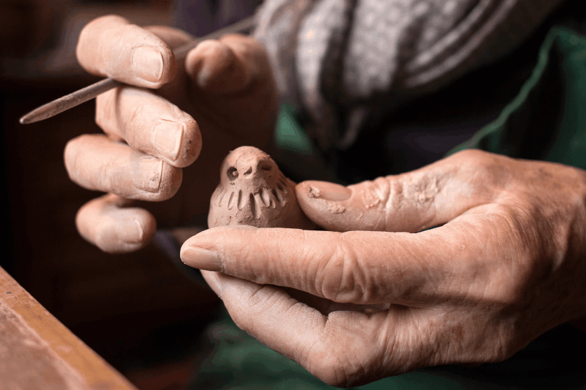 Old person making a clay bird 